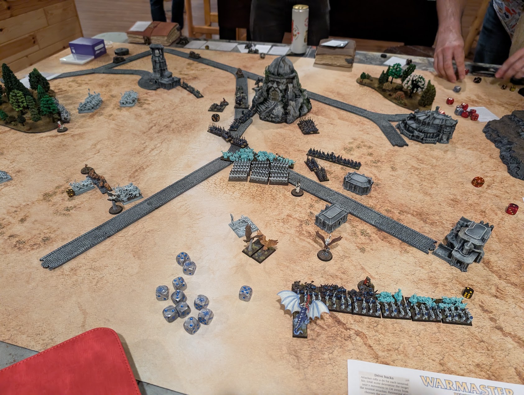 Warmaster armies face one another across a broad battlefield crisscrossed by stone roads and dotted with ruins.
